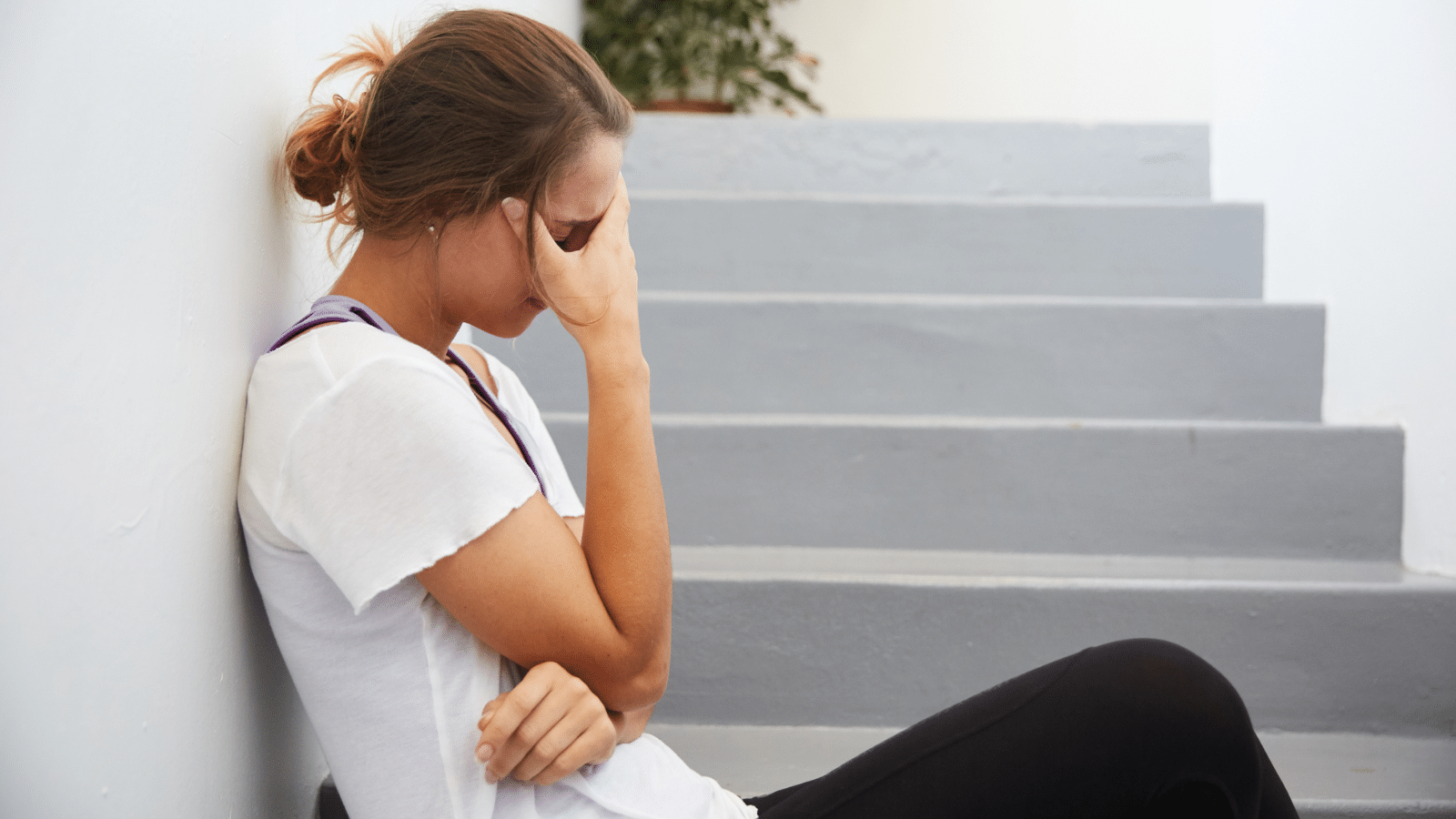 A woman sitting on stairs looking stressed.