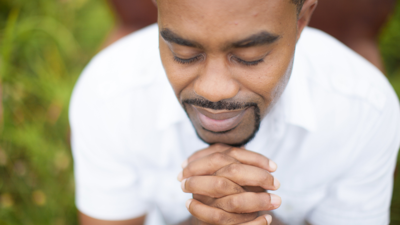 A man in a white shirt praying.