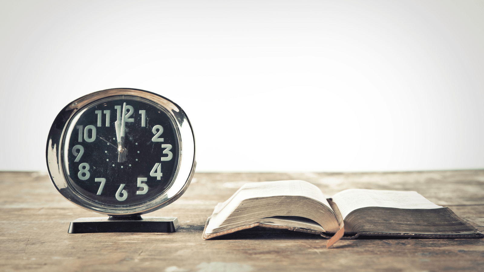 A clock next to an open book.