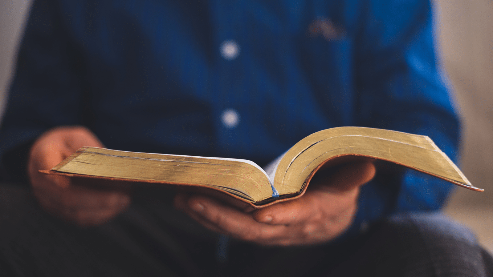 An older man holding an open bible.