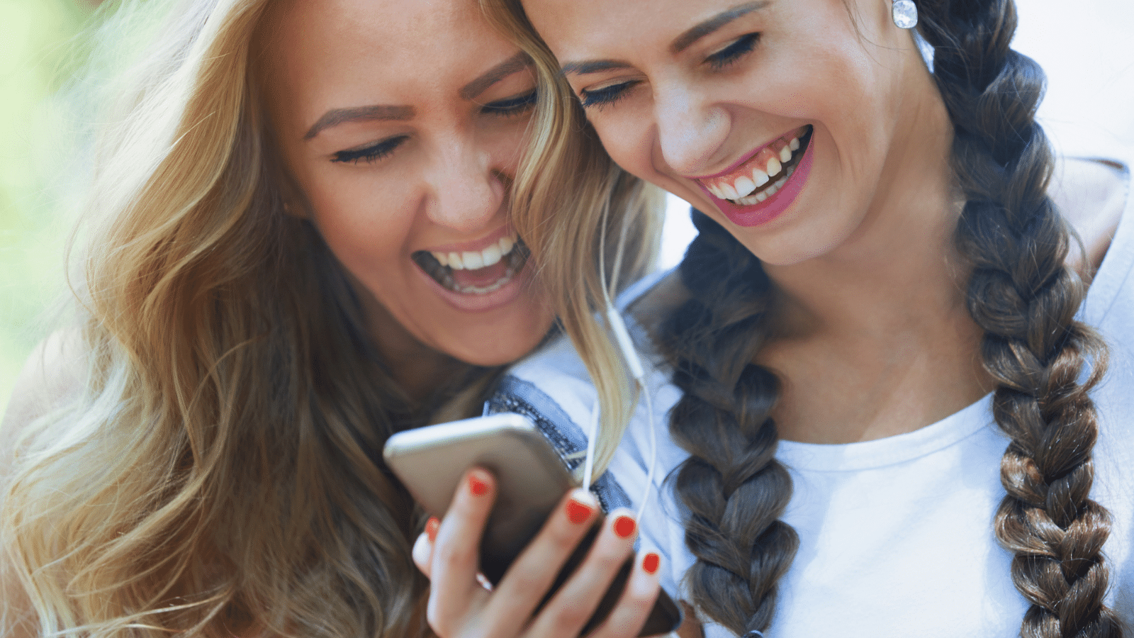 two women laughing at their phone