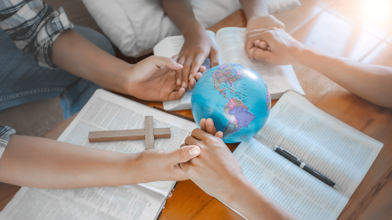 hands on a globe at a small group Bible study