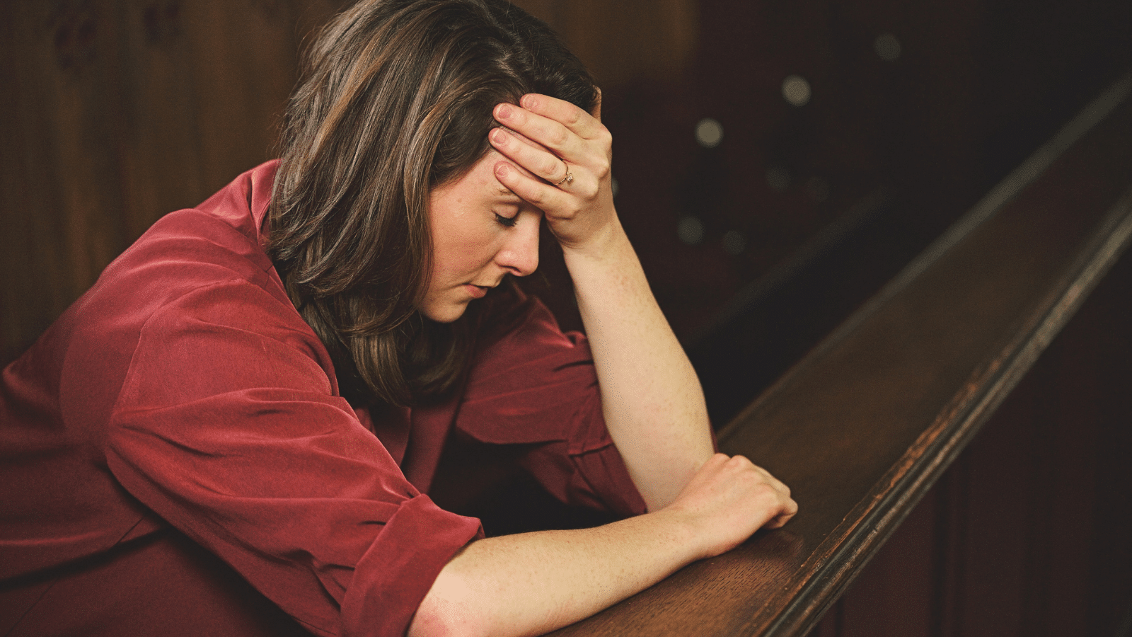 A woman sitting in a pew looking sad.