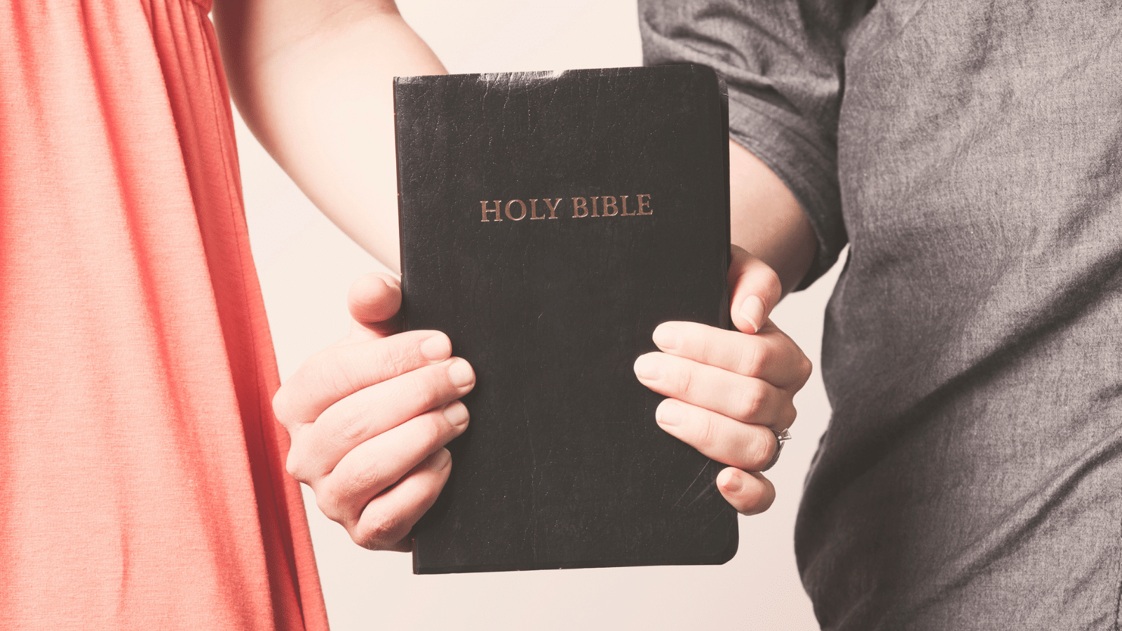 A man and a woman holding a bible together.