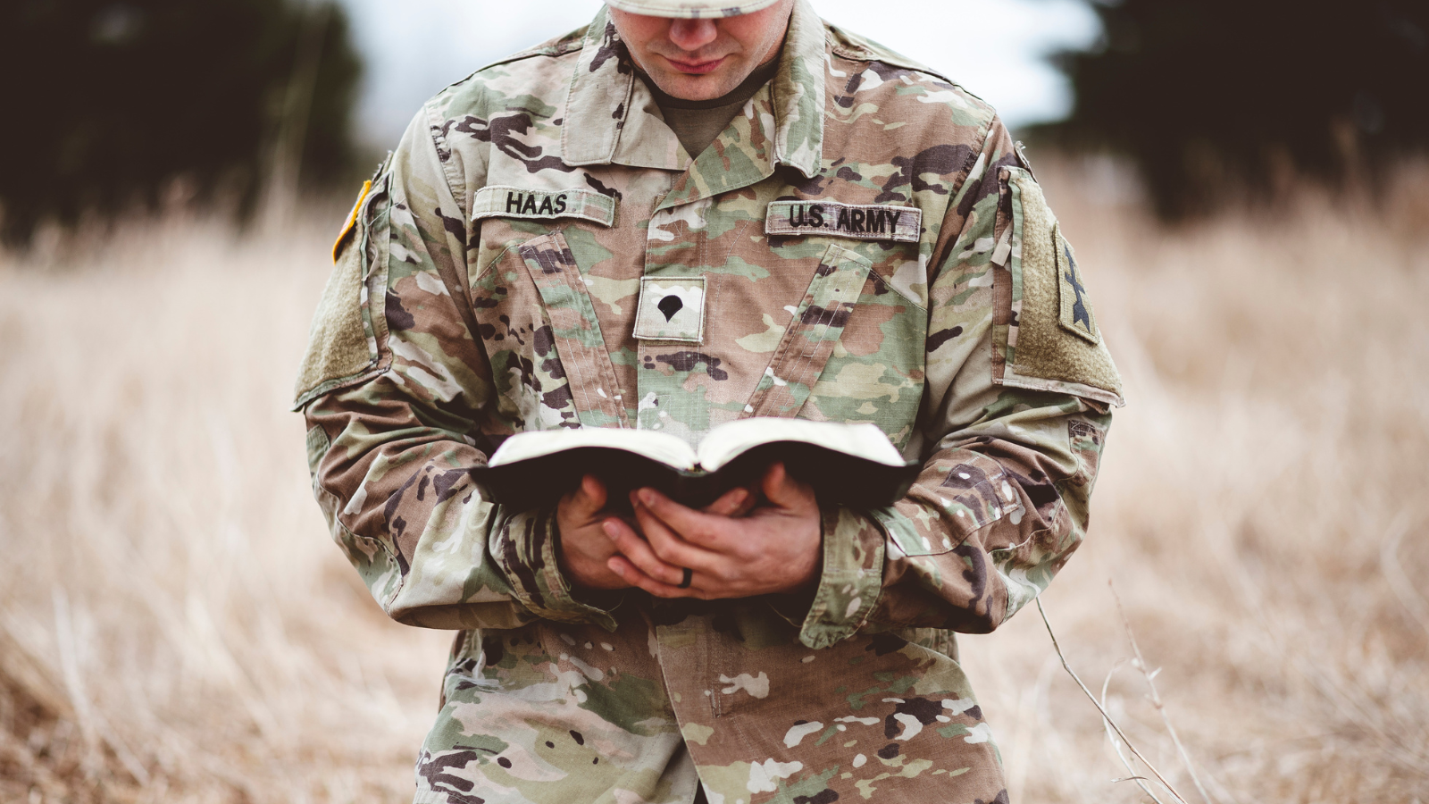 A man wearing a military uniform and reading a bible.