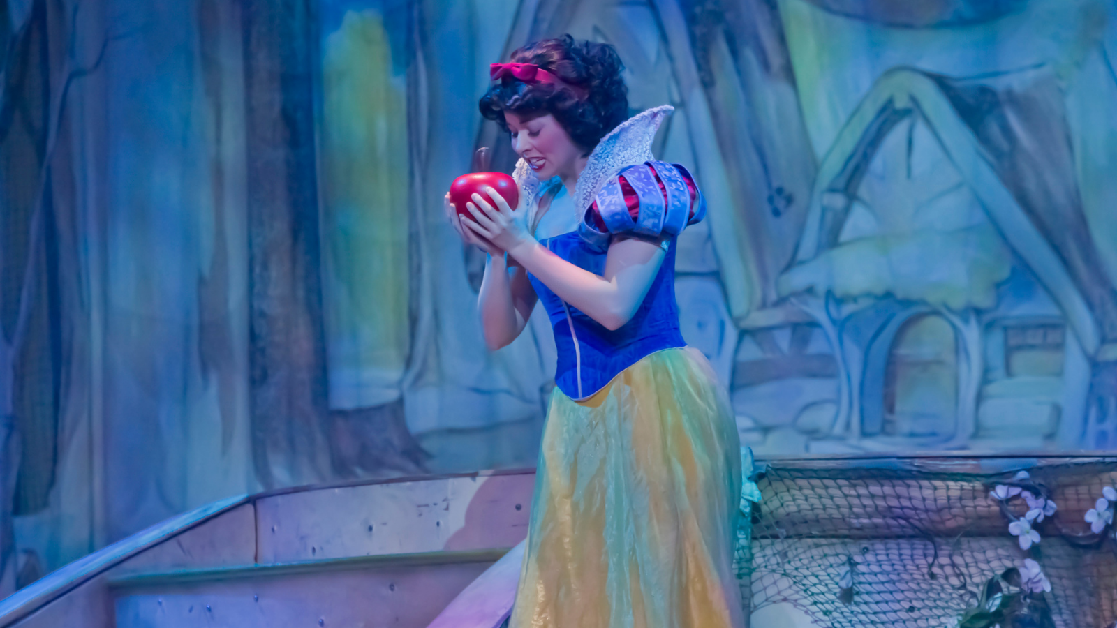 A woman dressed as Snow white holding an apple.