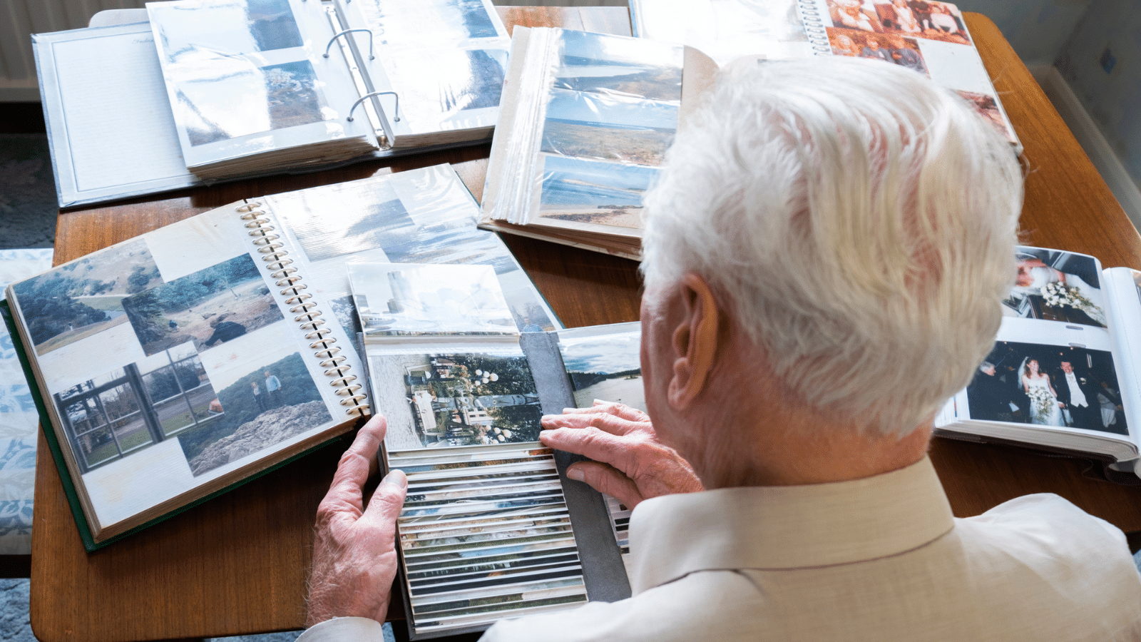 A man looking at multiple photo albums.