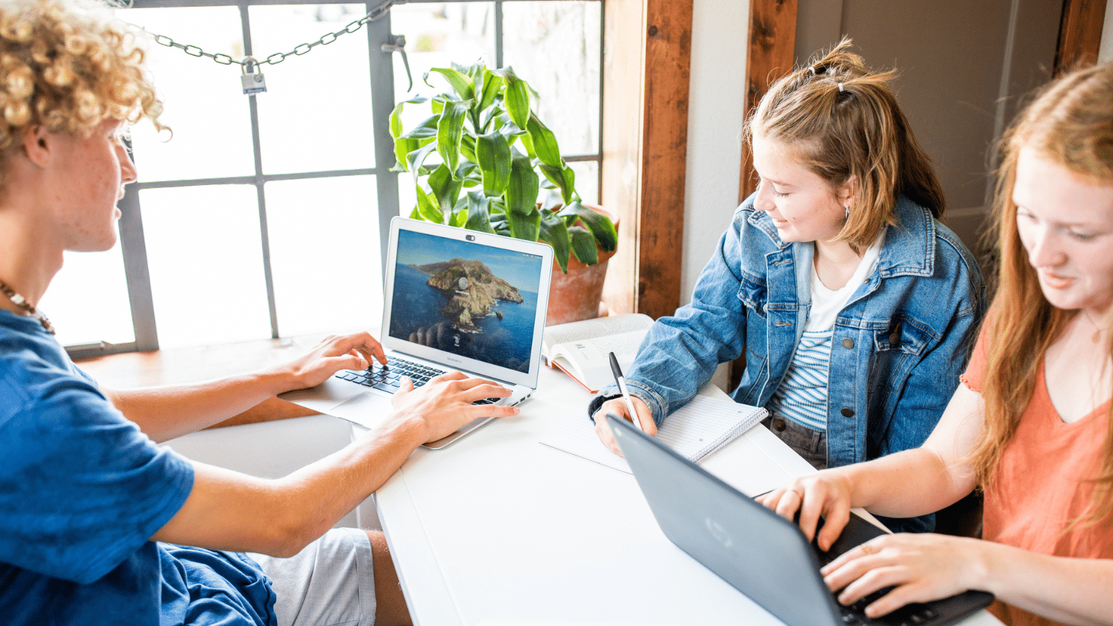 Three teenagers at a table doing school work.