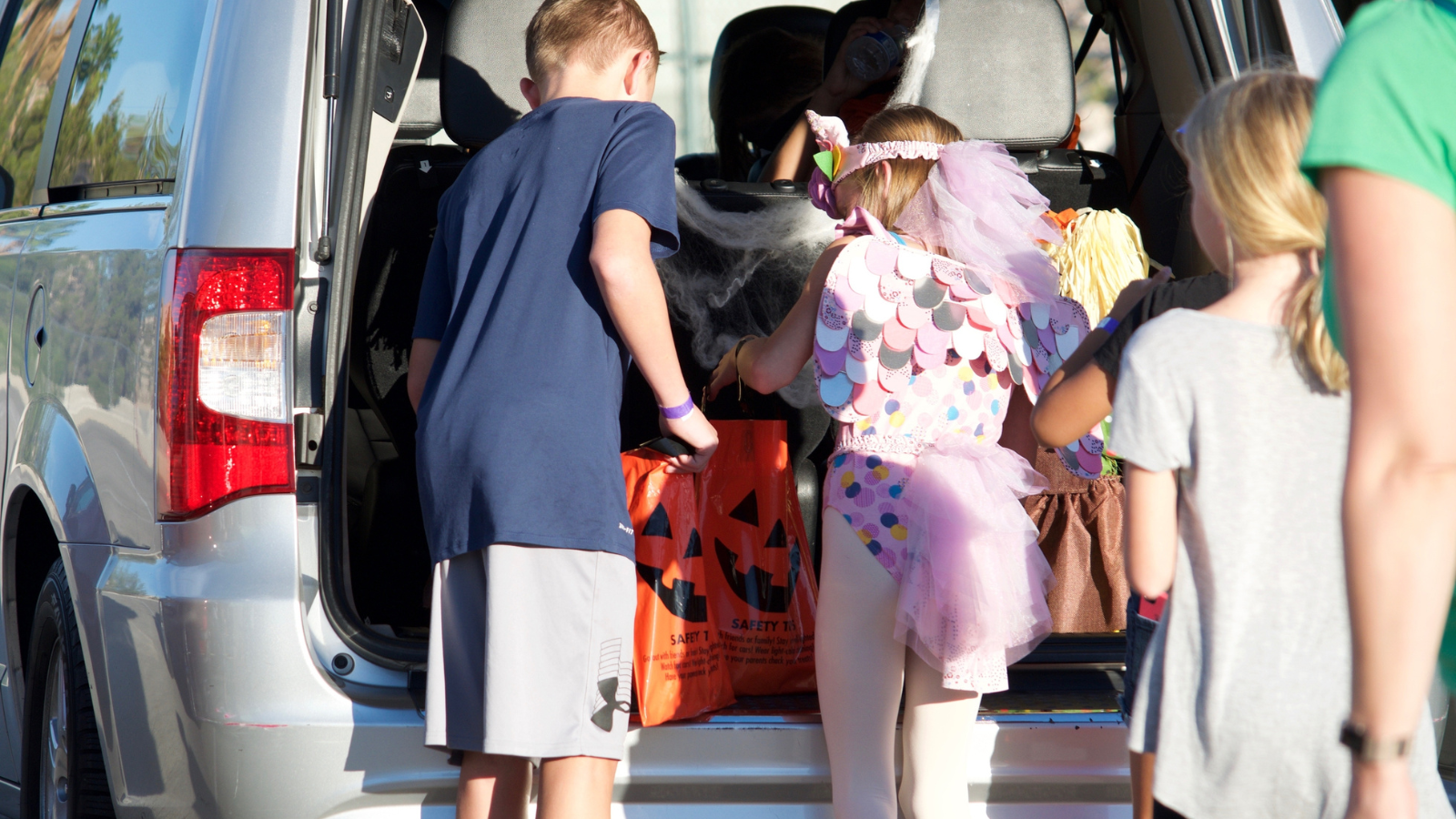 Some kids trick or treating out of the trunk of a car.
