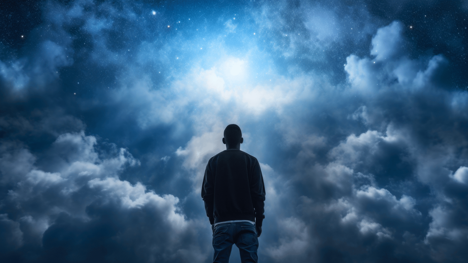 A man standing in front of dreamy clouds that look like heaven.