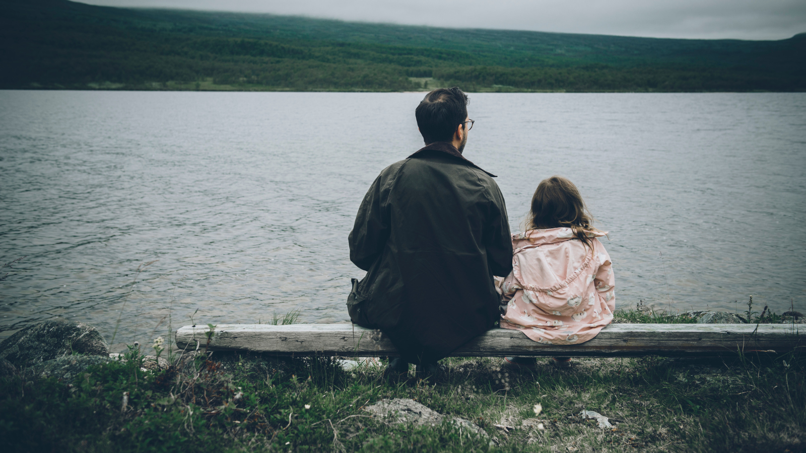 A man sitting with his daughter on a bench.