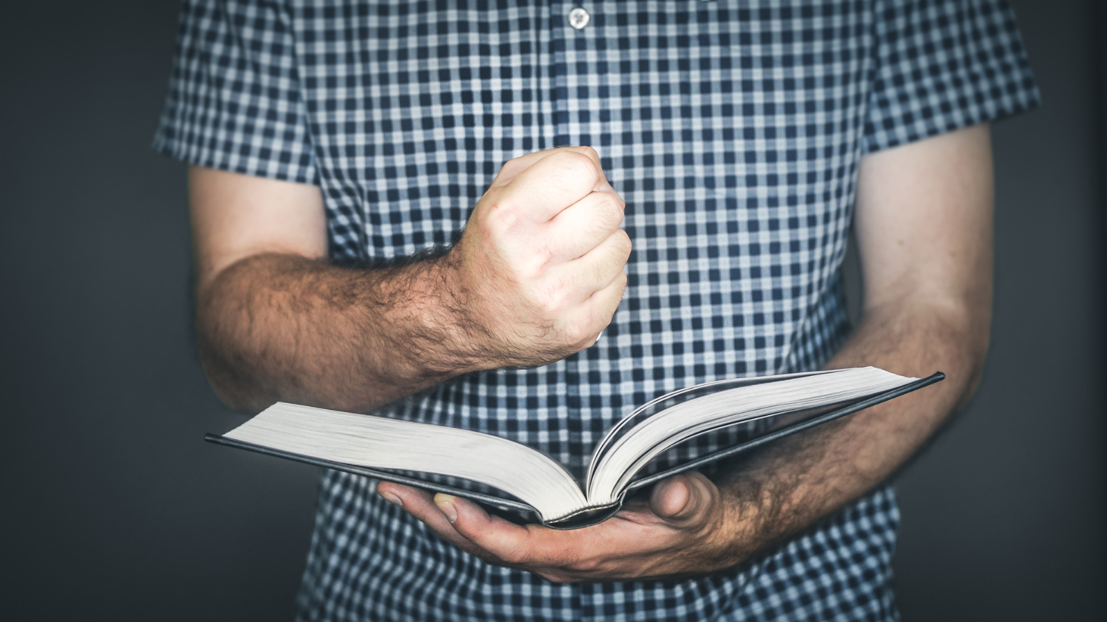 A man holding a fist above an open bible.