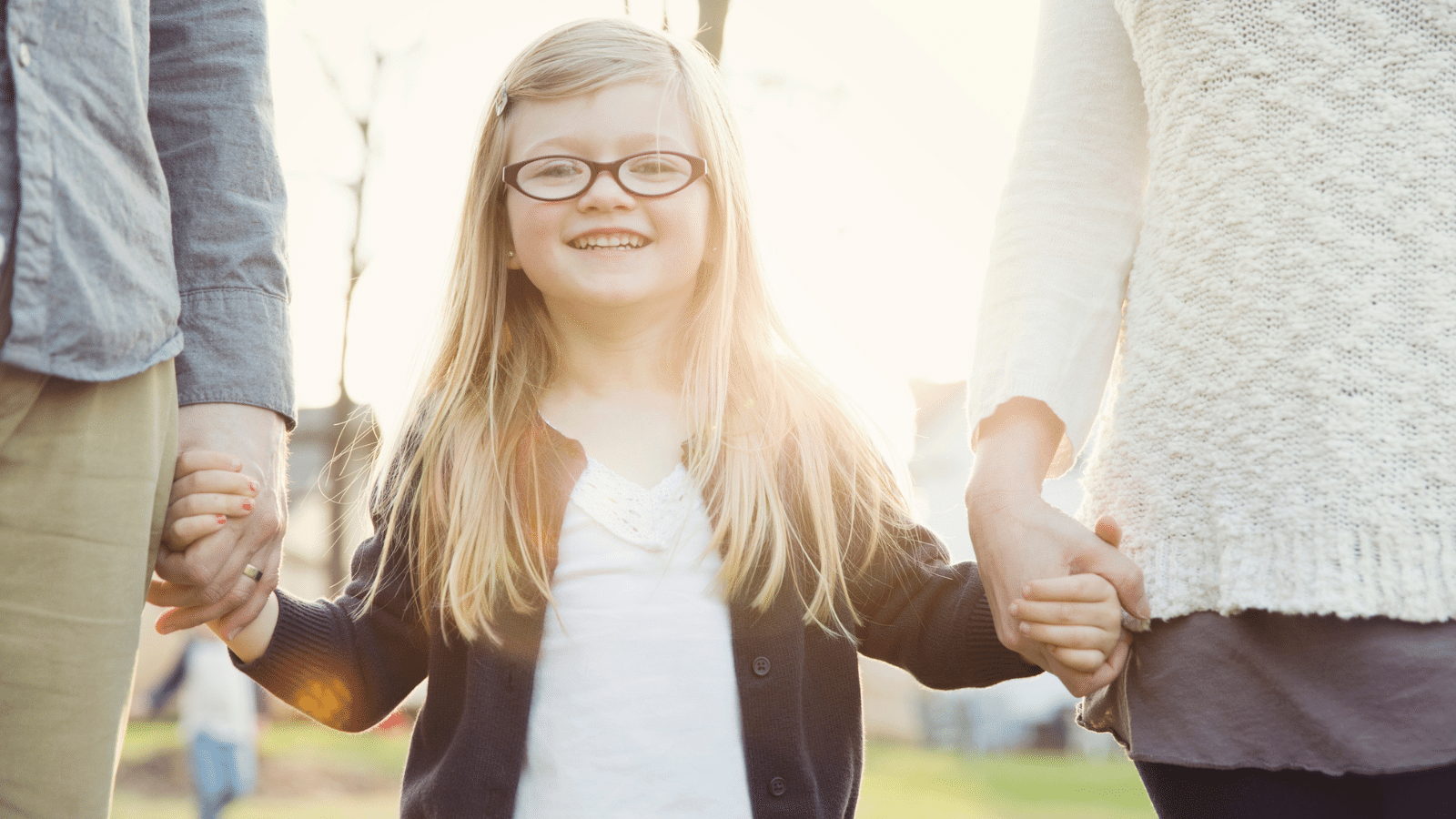 A little girl hoding her parents hands.