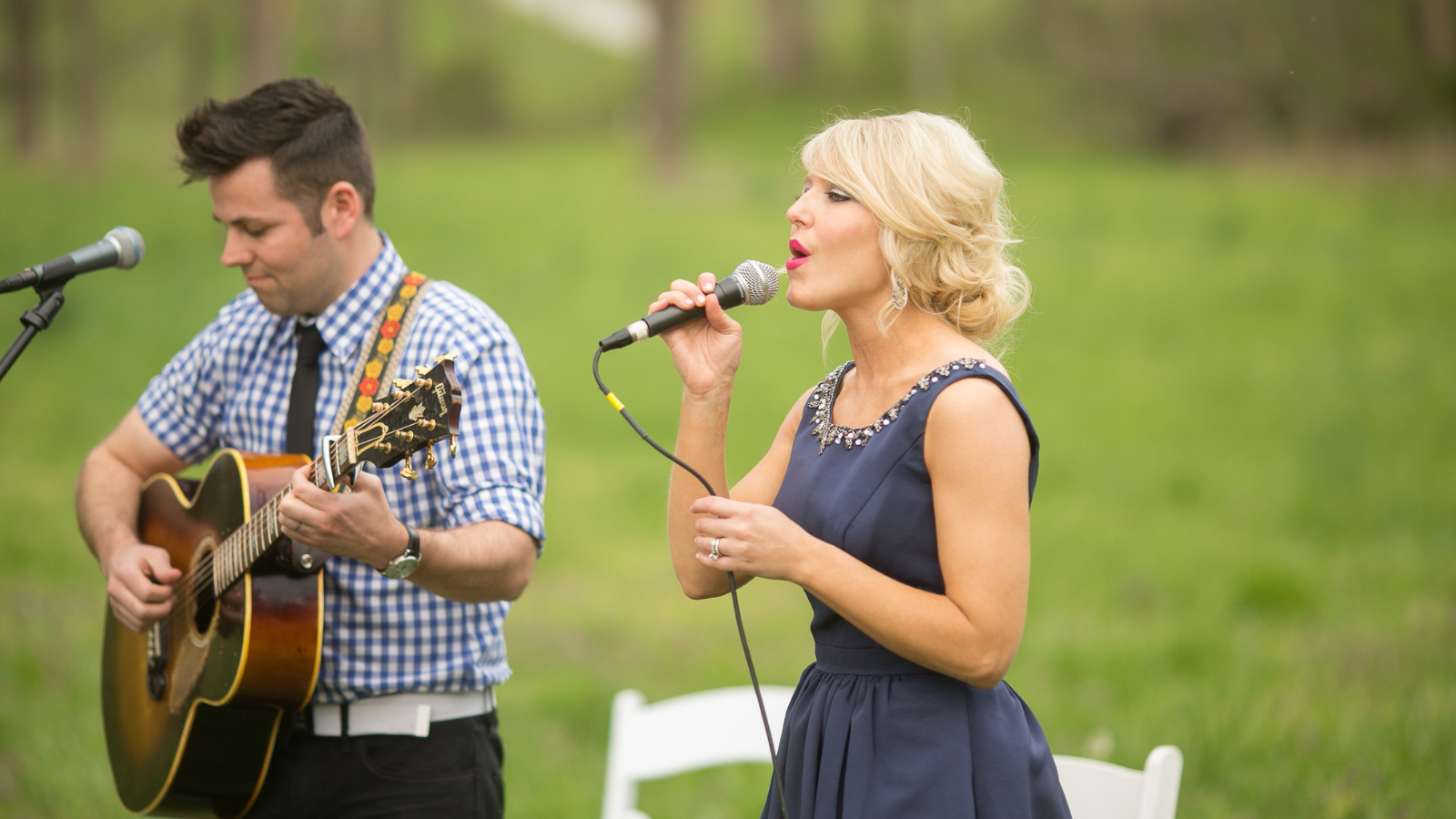 A woman singing next to a man playing a guitar.