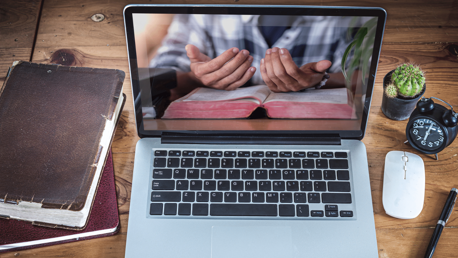 A man praying on the screen of a laptop.