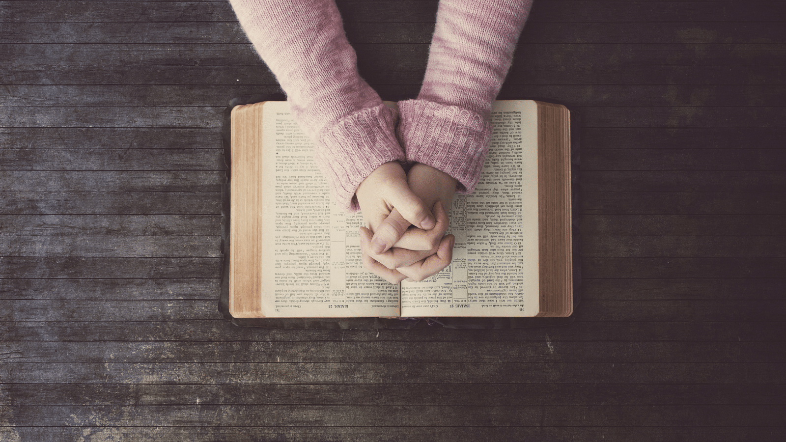 Woman with praying hands over a Bible