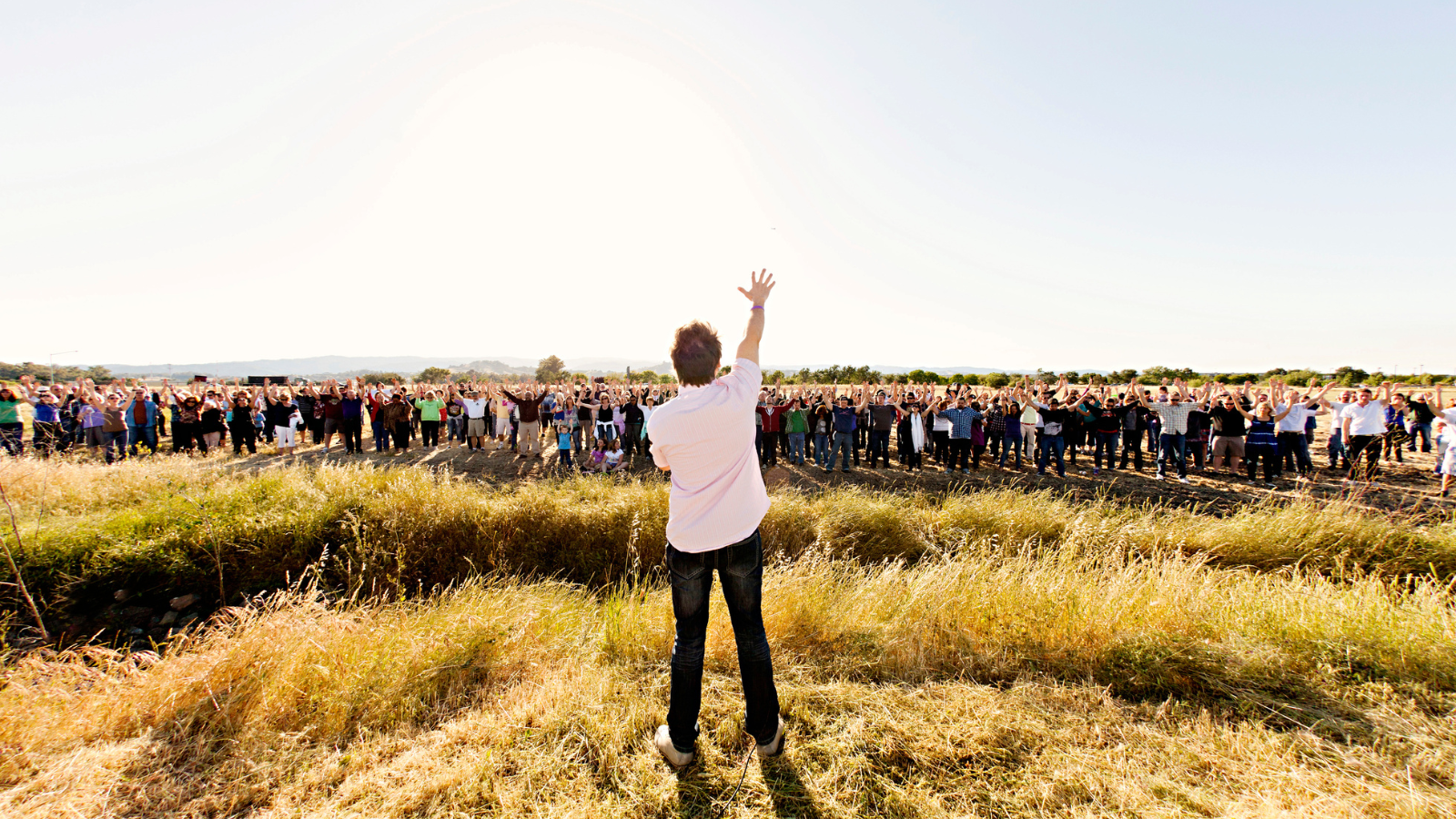 A man speaking to a crowd of people in a field