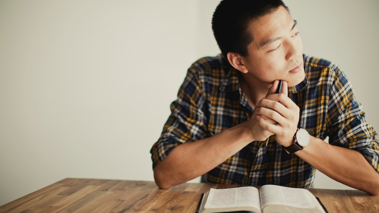 A young man thinking with an open bible.