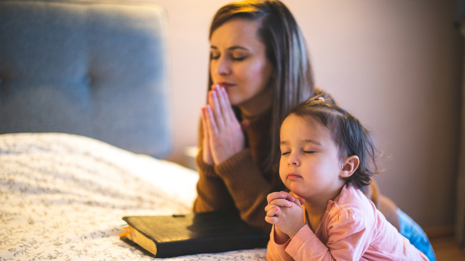 A mom praying with her daughter.