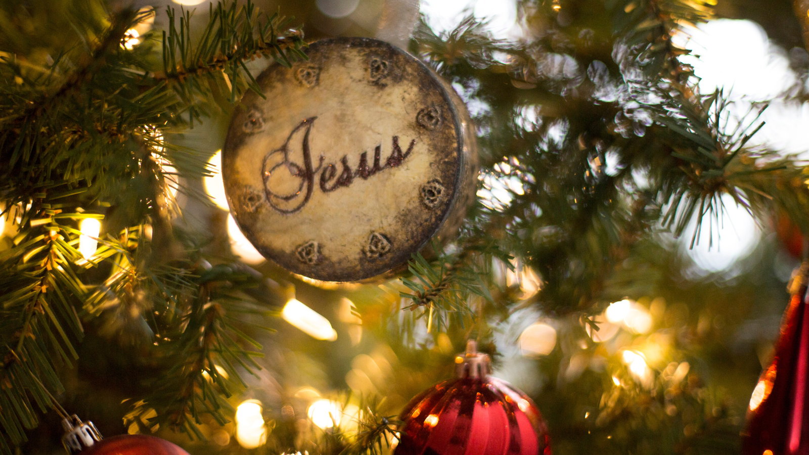 A Jesus ornament on a Christmas tree.