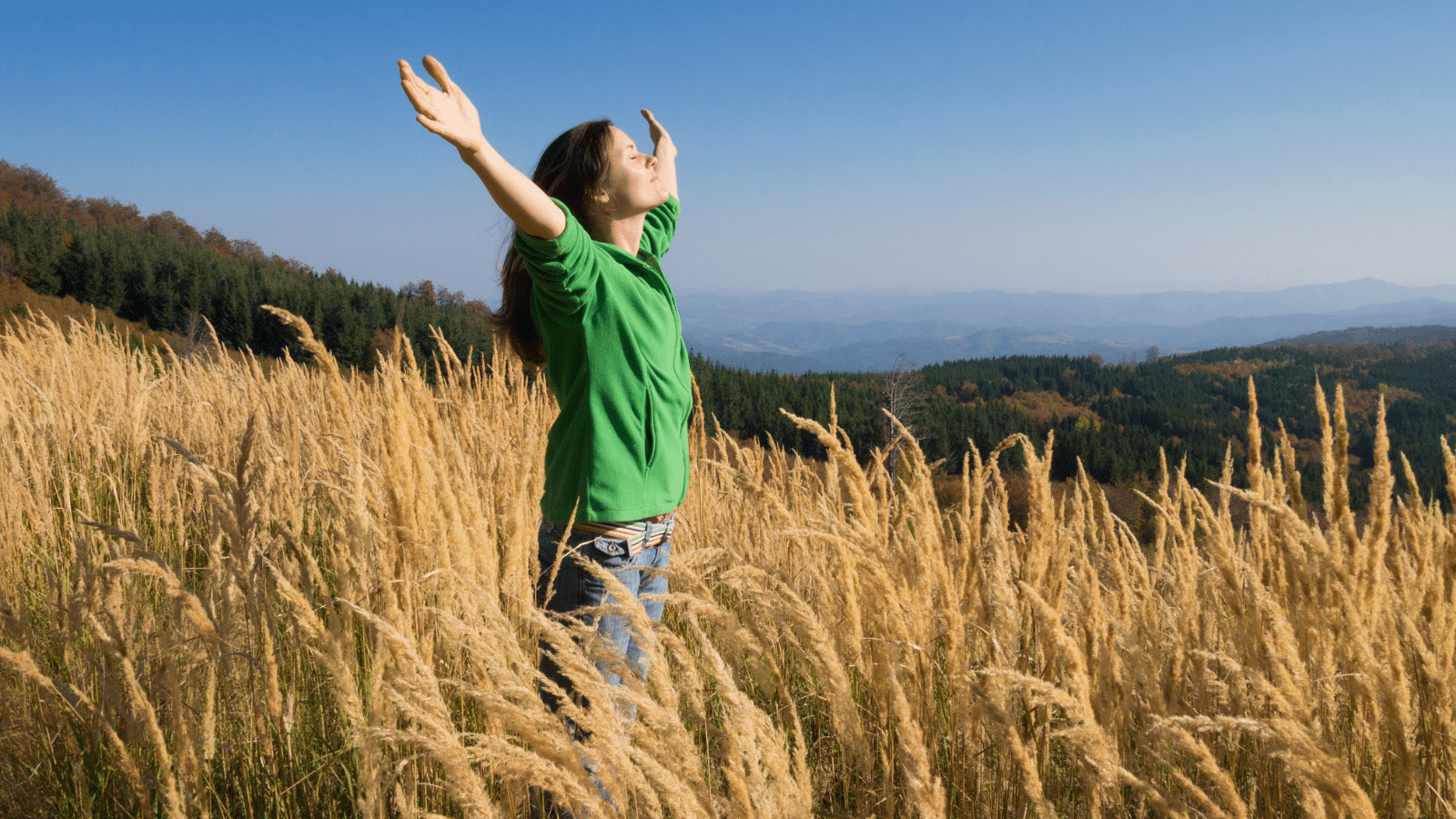 woman with arms raised in a wheat field