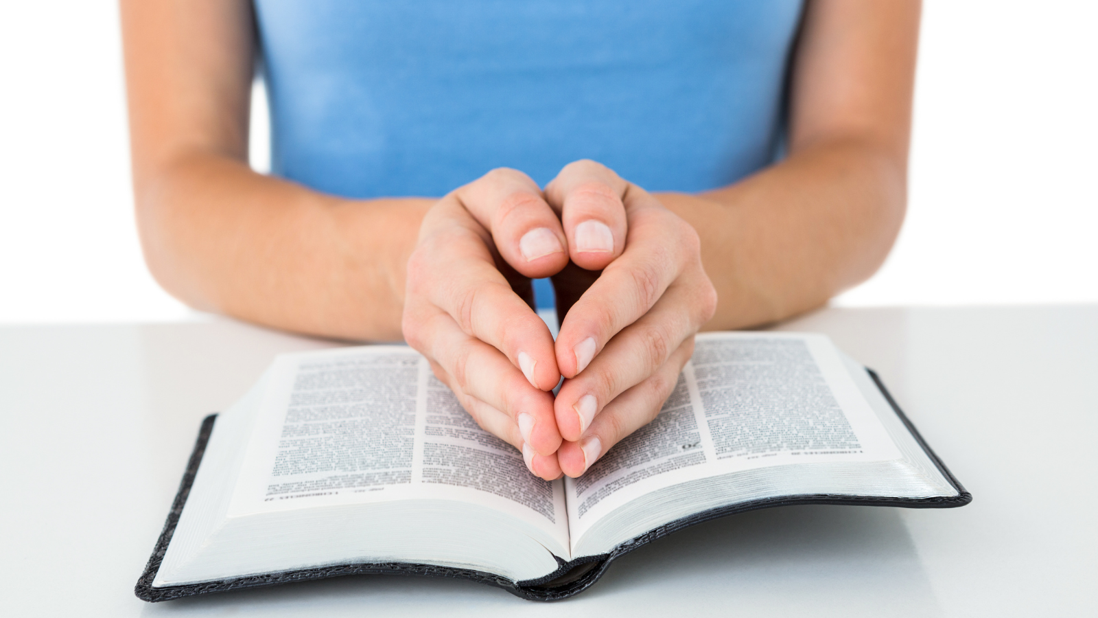 woman reading Bible with praying hands