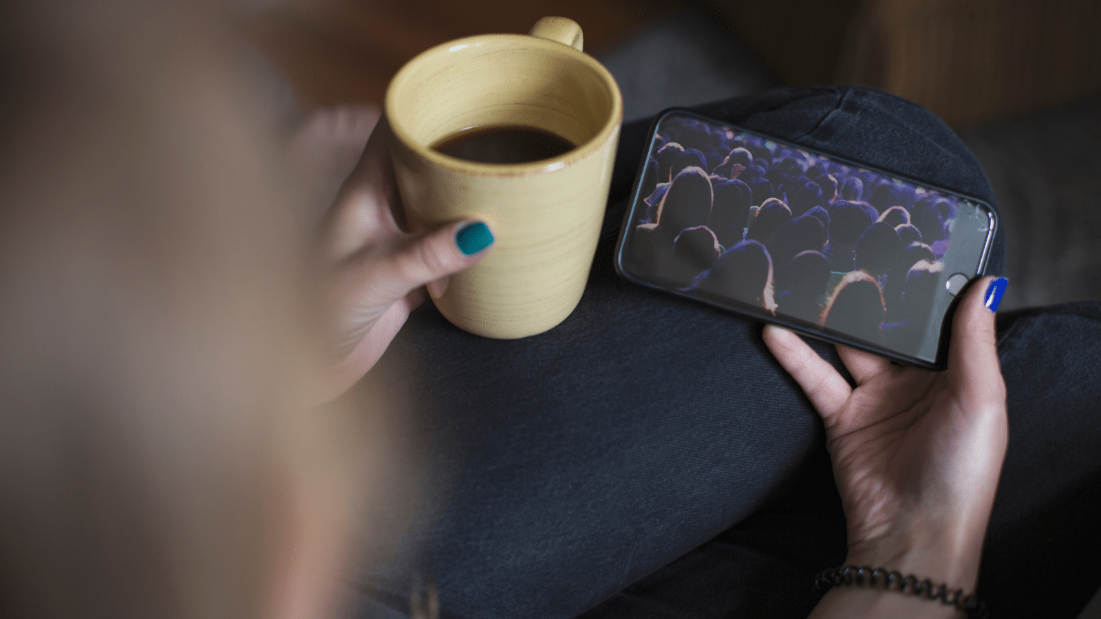 A woman holding a coffee cup and her phone.