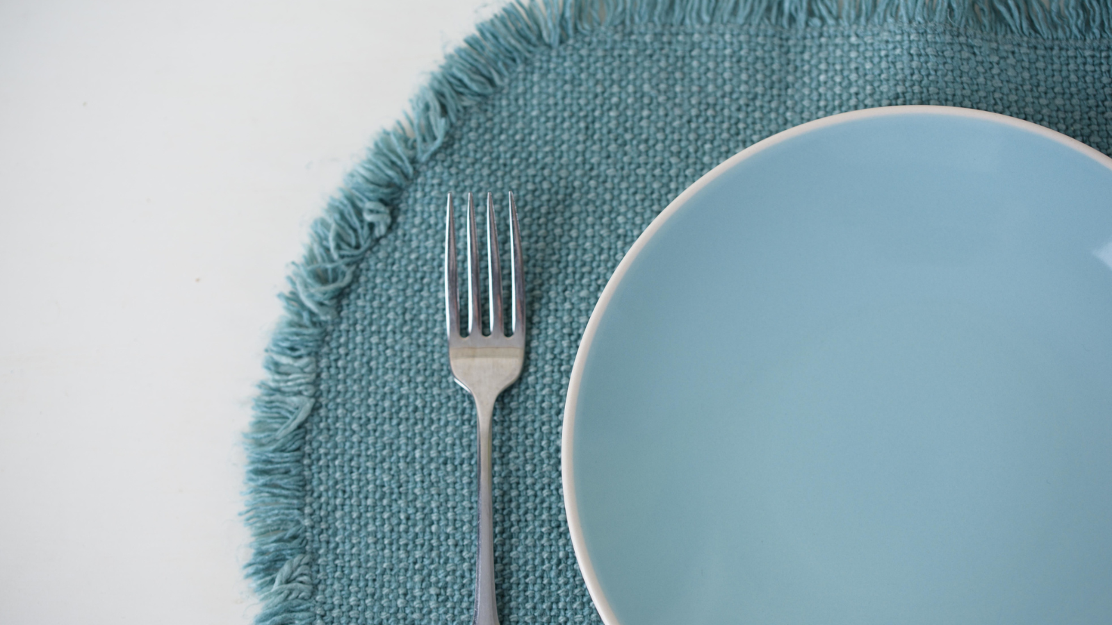 Blue plate on a blue mat with a fork