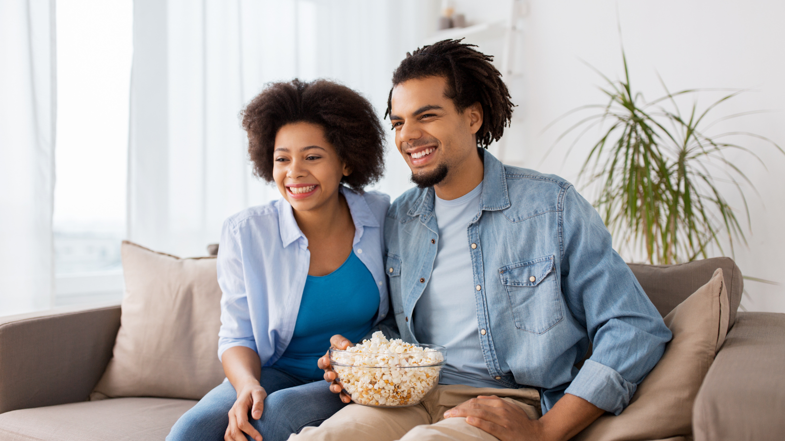 Man and woman sitting on couch with popcorn