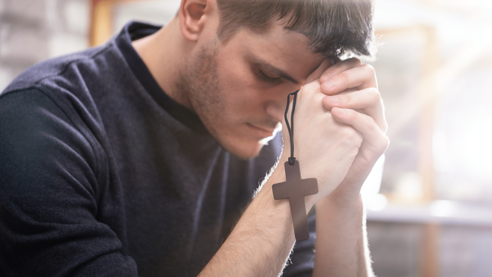 man praying with cross