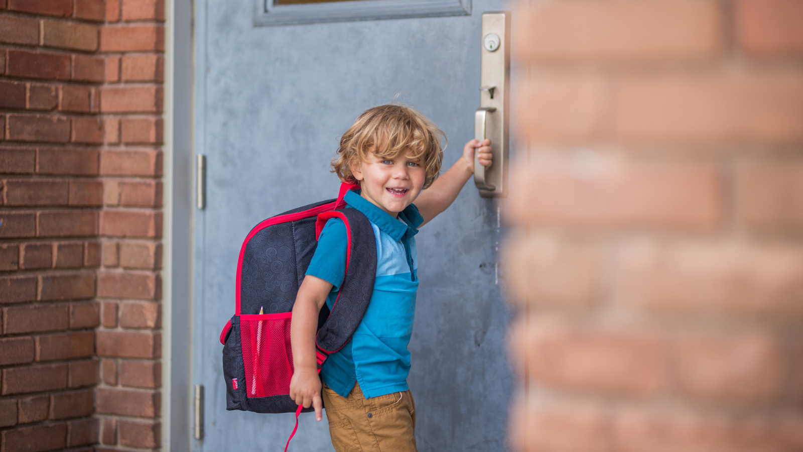 Boy wearing a backpack going into a school