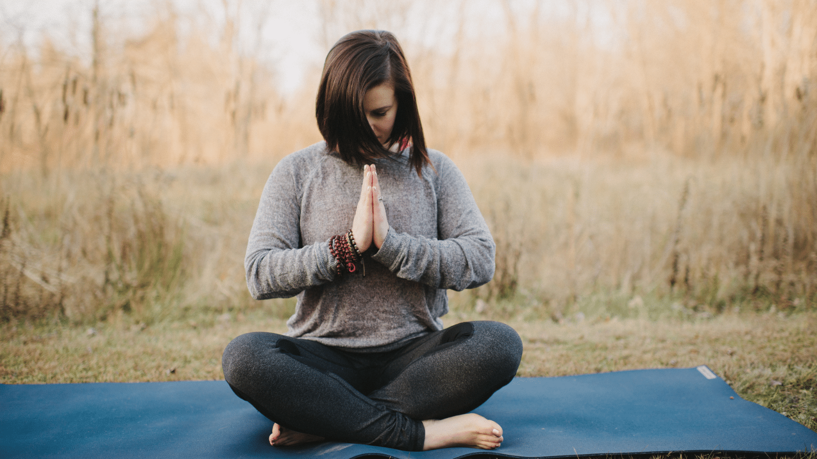 Woman sitting in a field in a yoga pose