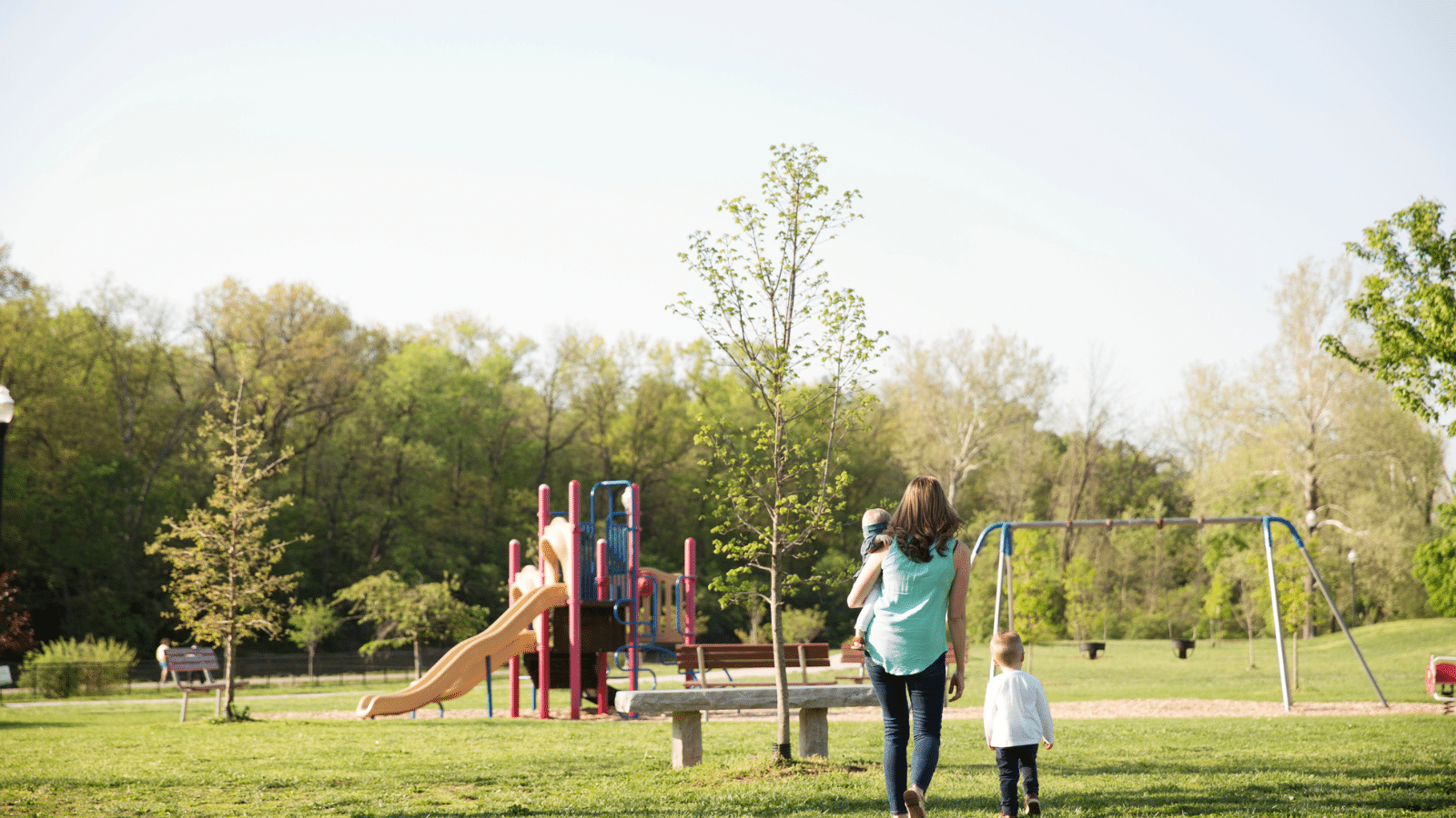 Woman walking with 2 kids to the playground