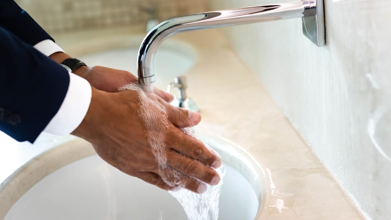 man washing hands in sink