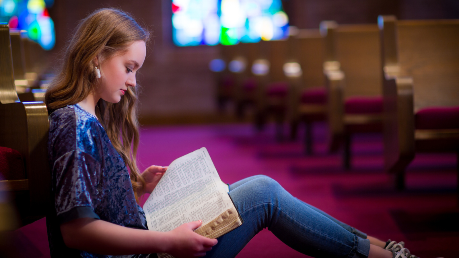 woman sitting reading the Bible in church