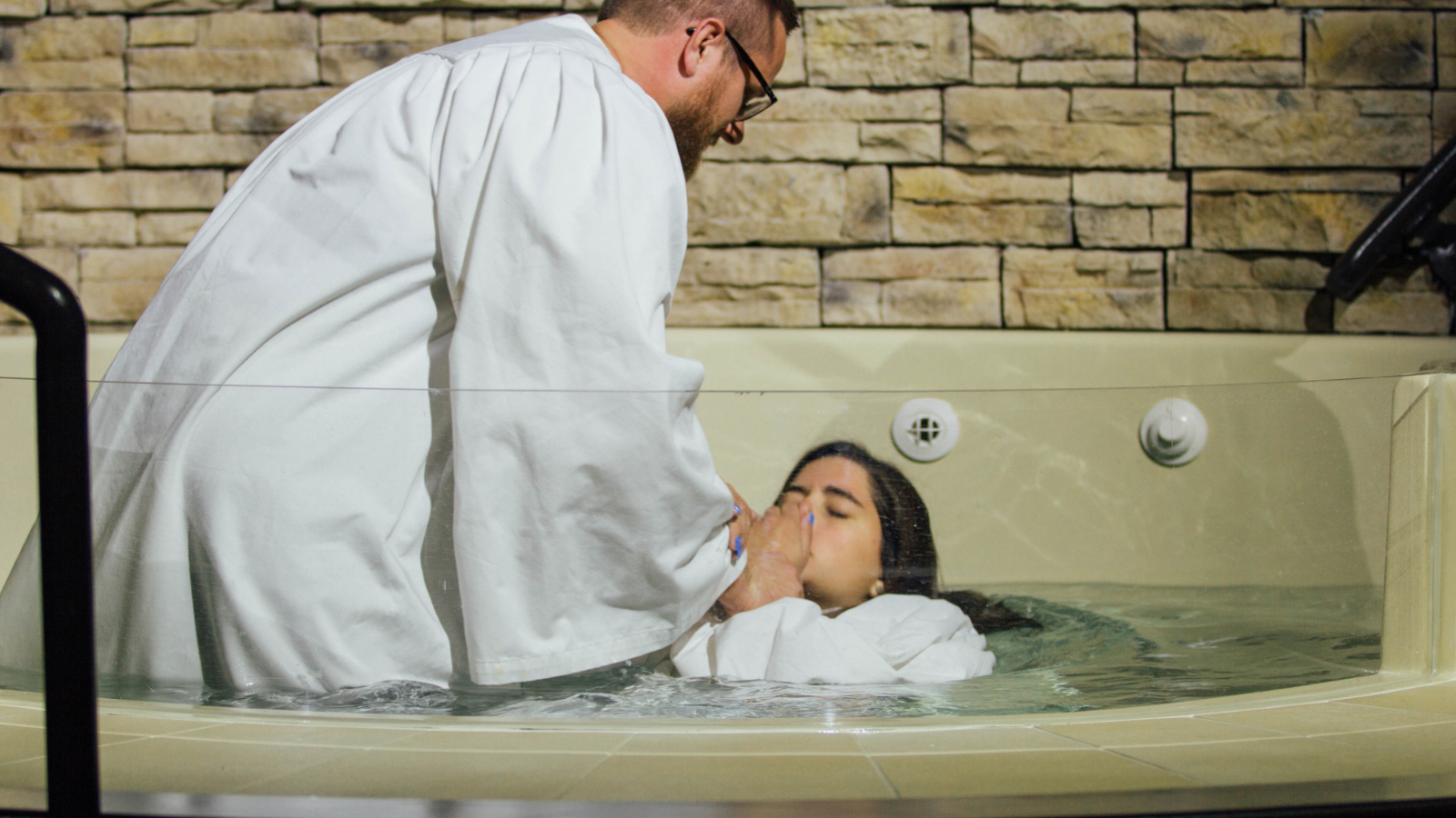 Girl being baptized in a baptismal