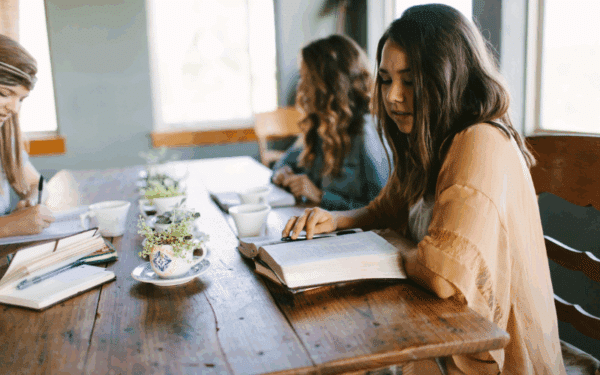 Young women sitting around a table reading their Bibles