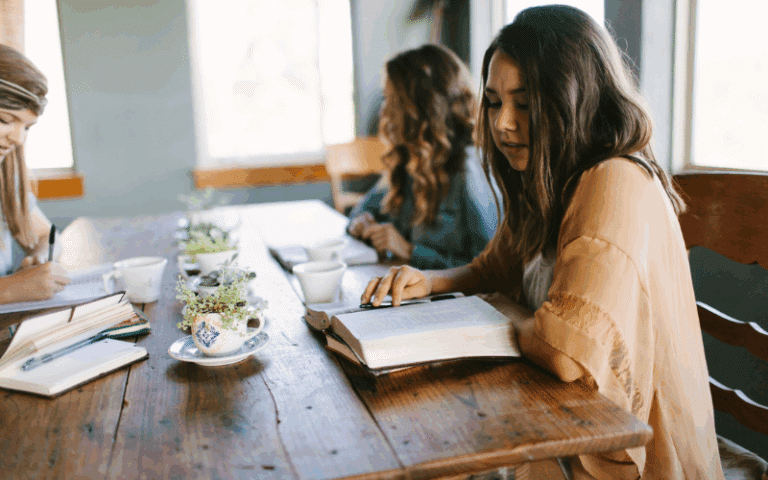 Young women sitting around a table reading their Bibles